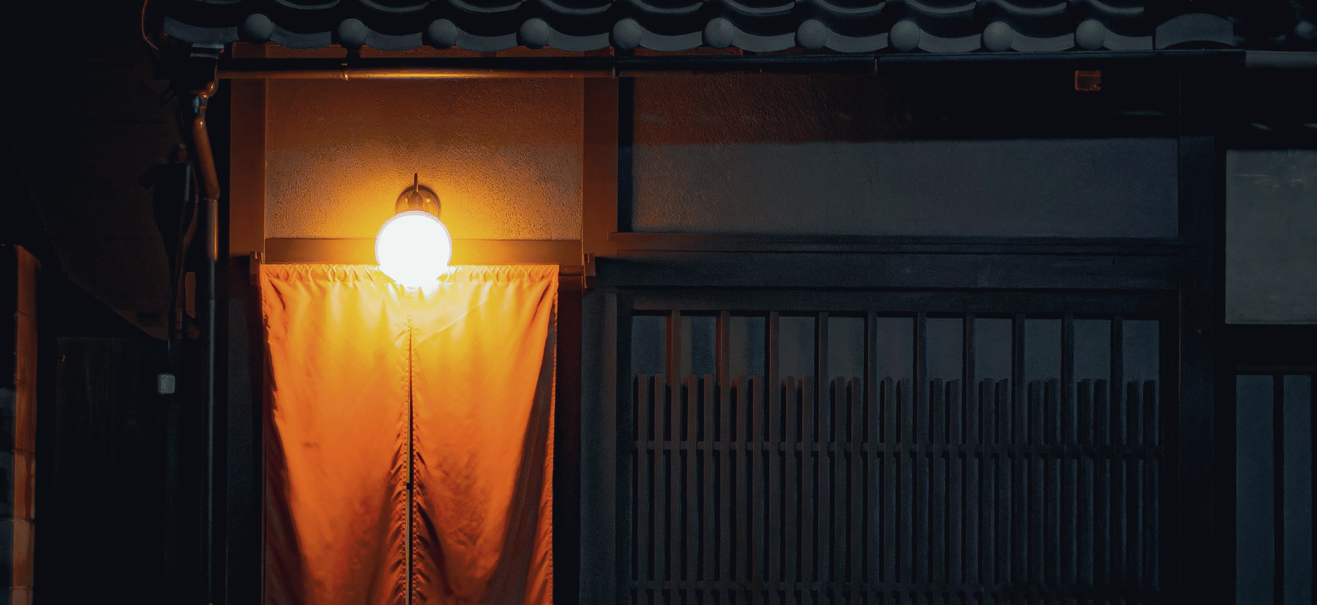 夜、暖簾に灯りがともる継屋の入口